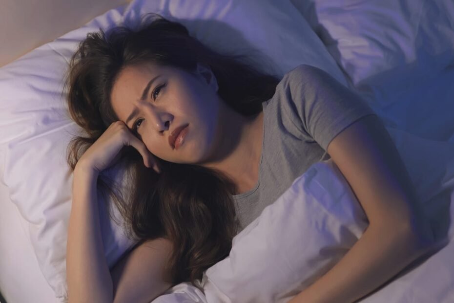 Woman who is laying in bed awake and unhappy about it