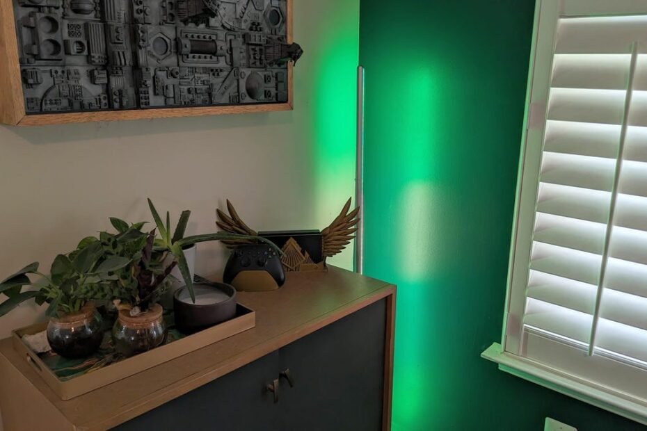 a green light glowing from a floor lamp next to a cupboard with plants on top